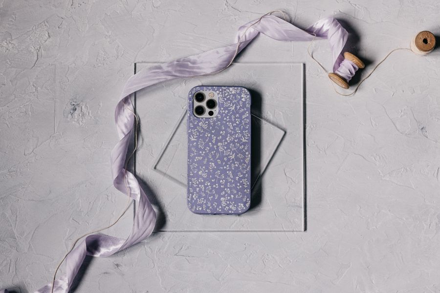 Aesthetic floral phone cover on a smartphone styled with a lavender ribbon on a soft textured surface
