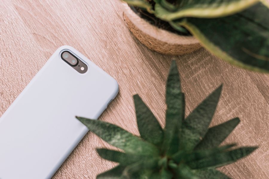 Minimalist flat lay of a smartphone on a wooden desk, representing personalized phone case gift ideas